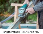 A man working with electric grinder tool on Steel beam. sparks flying. Electric grinding. Remove rust