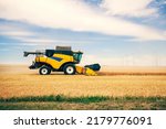 Small photo of Combine Harvester Cutting Wheat, modern combine harvester working on a wheat crop. combine harvester working on a wheat field. Harvesting the wheat. Agriculture.