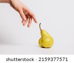 A hand touches an unusual pear-shaped remake of the renaissance and the creation of adam. The concept of cultivation of new varieties of fruits and vegetables, human impact on agriculture and nature