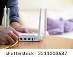 Small photo of Selective focus at router. Internet router on working table while technical guy lug fiber cable for on site service. Fast and high speed internet connection from fiber line with LAN cable connection.