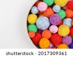 A lot of colorful wool balls of knitted yarn in a round cardboard box on a white background.The concept of handmade work, needlework and the sale of thread.Top view.Flatlаy.Rainbow layout.Copyspace.