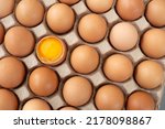 Small photo of Flat lay Close-up view of raw chicken eggs in egg paper box. One egg cracked showing the yolk. Top view Natural organic egg. Fresh chicken eggs, organic eggs, eggs for food ingredients, healthy food