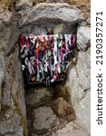 Small photo of Vertical shot of the entrance to the Ancient and Holy Well in Dillon's Park, in Dalkey, Ireland. Colorful ribbons tied on the entrance gate.