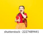 Small photo of A schoolgirl with a satchel is getting ready to go to school. Children's education. Preparatory courses for schoolchildren. Additional classes for successful exams. Yellow isolated background.