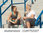 Small photo of Senior man and young asian girl having a rest sitting on the ground. A little breathing space after running in the city at early morning.