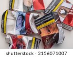 Small photo of Neckargemuend, Germany: May, 13. 2022: several crumpled cigarette packs of different brands with warnings in German language as a symbol for smoking cessation and quitting smoking