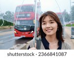 Smiling woman holding an umbrella on a rainy day with a bus in the background