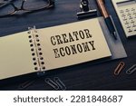 There is note book with the word Creator Economy on a laptop. It is an eye-catching image.