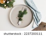 Top view of Christmas or New Year table setting with ceramic plate, fir branch with decor and cutlery. copy space