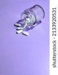 Small photo of Vertical shot. Medicines, in pills on the light mauve background and in a small glass container. Copy space.