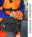 Small photo of Ticket collector from boat transportation with Ticket in hand.