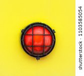 Small photo of Red alert bulkhead light fixed to a painted yellow orange colour wall background