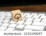 Small photo of Cloud computing download icon on wooden cube on a white computer keyboard. Remote download technology concept.