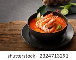 Small photo of Taste of Thailand: Spicy and Sour Thai Tom Yum Goong Soup with Shrimp and Aromatic Ingredients on Black and Wooden Background