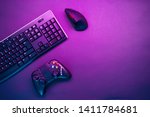 Keyboard, mouse and joystick on violet table background.