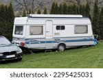 Small photo of Disengaged white camper in the yard with a black car next to it.