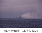 Small photo of North Sea - 07 27 2023: Car carrier on fire in the North Sea. The salvage tug attempts to extinguish the vessel on fire after the electro-vehicle explosion in the cargo compartment.