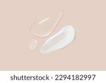 Small photo of Drops of transparent gel and a dab of white cosmetic cream. On a beige background.