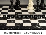 Small photo of The concept of Scrummaster represented by black letter tiles with chessboard background