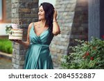 Small photo of Cheerful pregnant brunette in a green dress holds a birthday cake in her hands. a pregnant woman is expecting a baby and celebrates her thirtieth birthday.