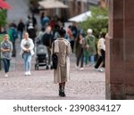 Small photo of Heidelberg, Baden-Wurttemberg, Germany - 08 03 2023: A woman in a topcoat under the gate of the Heidelberg bridge