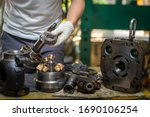 Small photo of Professional mechanic man holding bearing of the hydraulic piston pump to inspection and repair maintenance heavy machinery