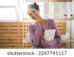 Small photo of Gentle sweet girl in purple sweater posing at camera smiling sincerely from. Radiant brunette woman with beautiful appearance holds diary in hands. Positive female student with notebook organizer