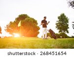 Full length portrait of handsome mature man playing golf at beautiful summer day on green course, professional golf player standing against amazing flare sunset light