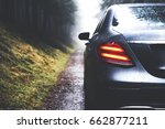 Small photo of Beautiful streamlined by rain drops car with modern design headlights. Luxurious business class automobile with silver grey color. Stylish rental vehicle. Weather conditions for a trip, copy space
