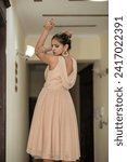 Small photo of ISLAMABAD, PAKISTAN - JANUARY 13, 2024 :Young beautiful classy girl standing on the floor in short frock dress in comfortable home interior
