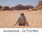 Small photo of Silhouette of man in tropic clothes, who is sitting on rock and looking at amazing Martian scenery of Wadi Rum desert with red sand. Jordan The Valley of the Moon