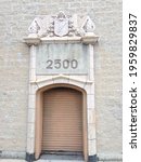 Small photo of CHICAGO, IL, USA - JUNE 28 2013: Ornate stone entrance, with coat-of-arms and incongruous roll-up door, to the building at 2500 N Milwuakee Ave at Logan Square.