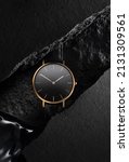 Small photo of Luxurious gold watch with a black dial. A watch on a beautiful black background with black stones. Women's, Men's fashion