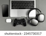 Set of modern gadgets on a beautiful dark or gray background with headphones, laptop, phone, joystick and camera
