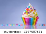 Small photo of Birthday cupcake. Rainbow paper cup liners. Happy Birthday. Celebration Holidays. LGBT pride. Tasty baking cupcakes, cake or muffin with white cream icing, frosting, bright colored sprinkles or candy.