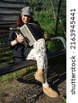 Small photo of Redhead lady sitting on a bench and playing a diatonic button accordion