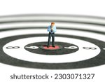 Small photo of Miniature tiny people toy figure photography. A businessman getting ready, justify the tie above dartboard