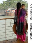 Small photo of Ganges Delta / Bangladesh - Feb 16 2006: A mother and child standing on the deck of the Rocket paddle steamer as the ship arrives at a small dock. Waterways of the Ganges Delta in southern Bangladesh.