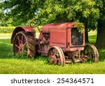 A Old Red Tractor Sits Under A...