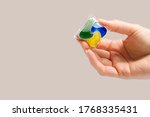 hand holds the Dishwasher Capsule on beige background. copy space. woman hand holding dishwasher detergent tablet.