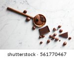 wooden spoon with caramel, chocolate chips and chocolate balls on white marble background