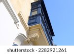 Small photo of Exterior of typical maltese houses and colorful wooden balconies, beautiful limestone buildings. Bottom up view of the blue wooden balcony with stucco.