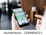 Hand of young woman searching location in map online on smartphone.