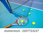 Tennis racket, ball and tennis ball box on hard blue court