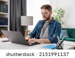 Small photo of Smart young man sitting at desk and working from home on modern computer. IT specialist programmer writing complicated code on digital laptop.