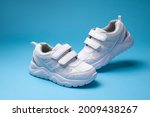 two white boys ' child shoes with velcro fasteners for the convenience of children's shoes, isolated on blue background.