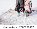 Small photo of Russian tradition of carpet cleaning. Close-up of woman and child with carpet beater in their hands engaged in ecological carpet cleaning with fresh snow on winter day.
