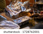 Small photo of Various food dishes covered in tin foil at a party or Thanksgiving