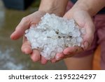 Woman hands holding hail stones in the garden after storm in the summer.