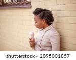 Small photo of Young African American woman eating pink ice cream in a crispy waffle cone, lifestyle, city walk, theism.